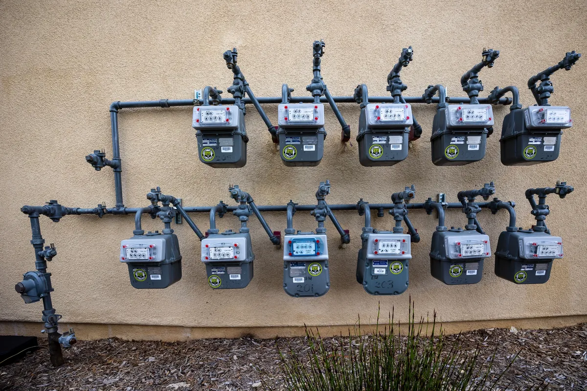 Commercial natural gas meter bank — eleven meters installed in two rows on an exterior building wall, served by D&S Utility Services